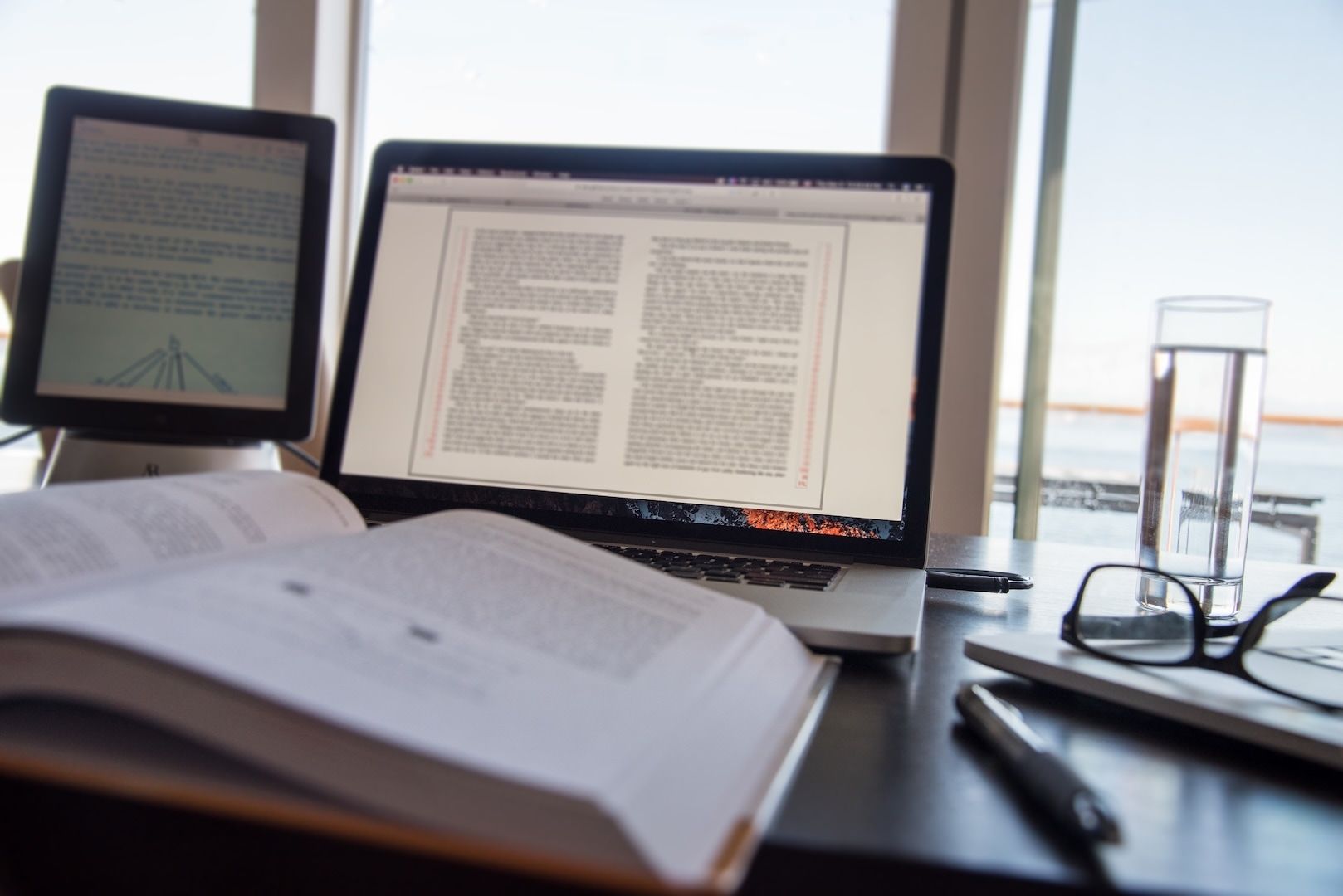 A printed book open beside a laptop