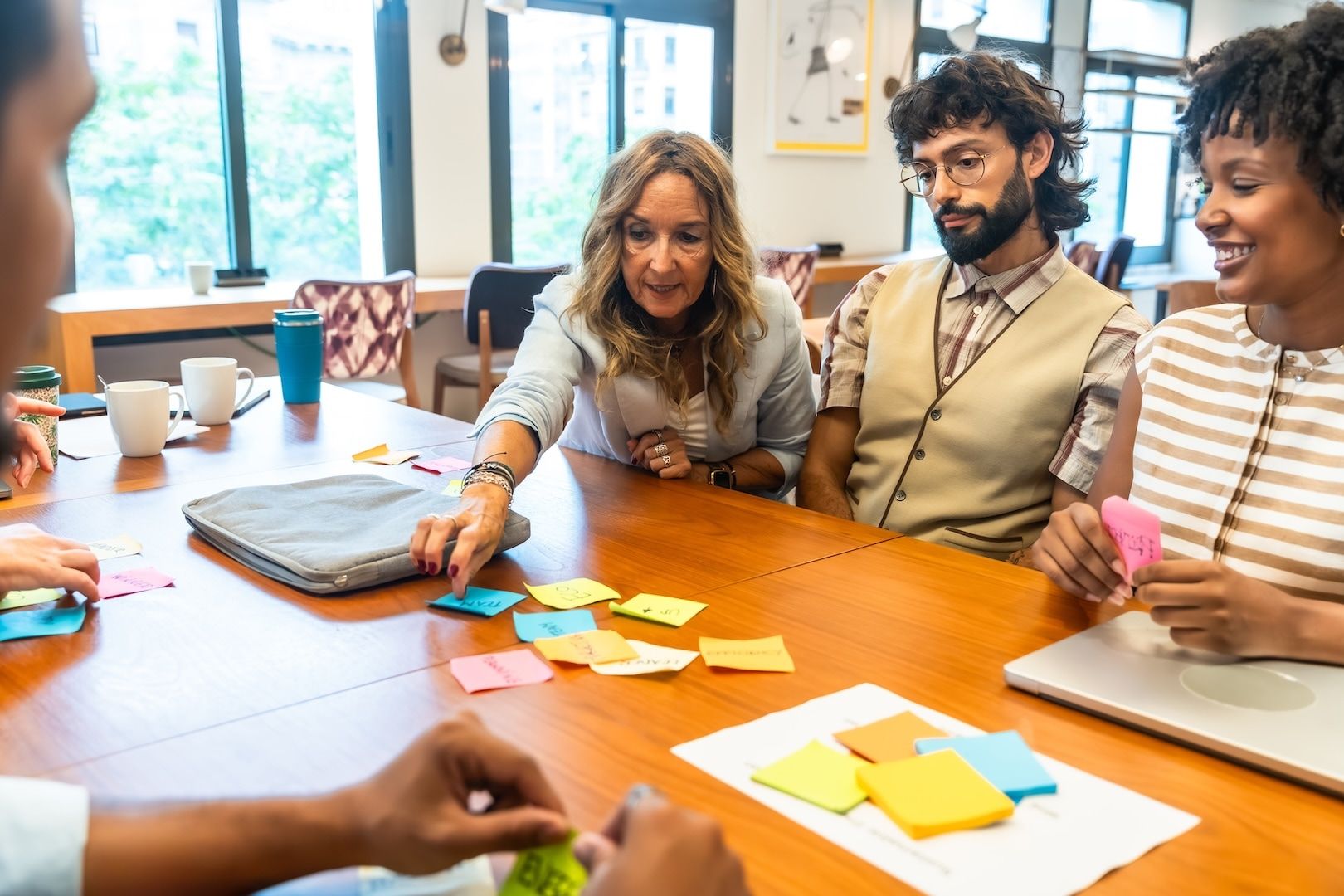 Colleagues arranging sticky notes on a wall while planning